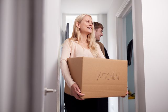 Group Of College Student Carrying Boxes Moving Into Accommodation Together